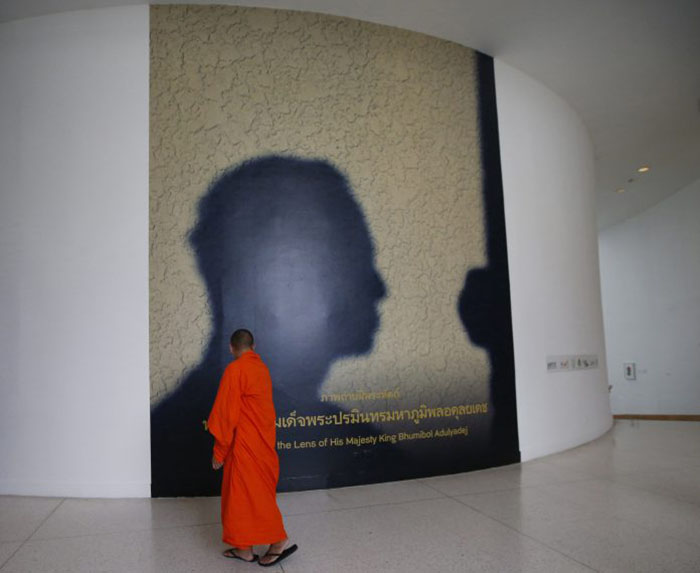 Буддийский монах проходит мимо билборда с автопортретом покойного Короля Пумипона Адульядета. Фото Сакчай Лилит Associated Press