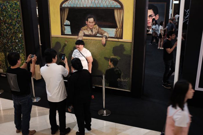 Посетители торгового центра в Бангкоке на выставке картин в память о Его Величестве Пумипоне Адульядете. Фото Тэд Энтони Associated Press