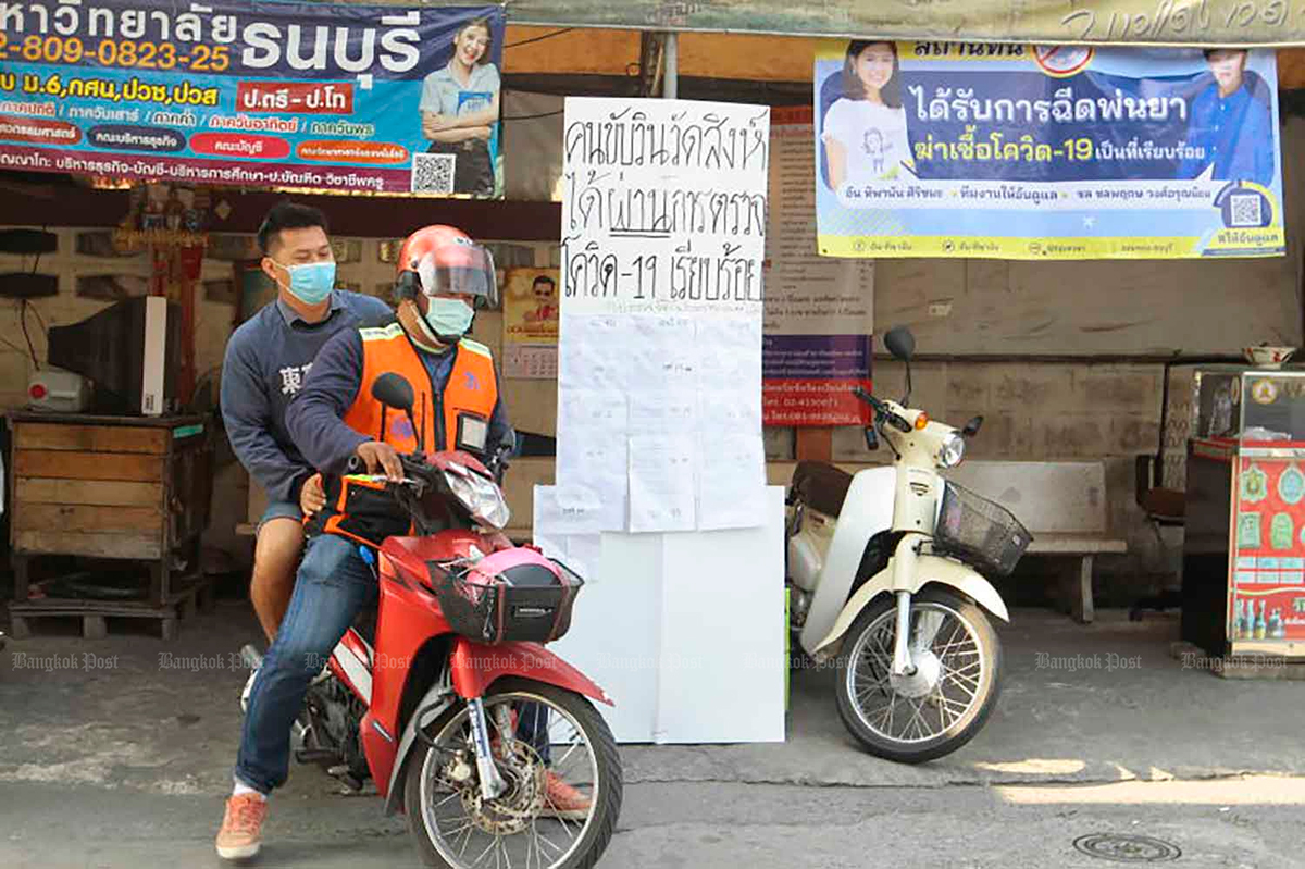 Водитель мототакси забирает пассажира. На стенде написан плакат о том, что водители прошли тестирование на коронавирус. Фото Bangkok Post